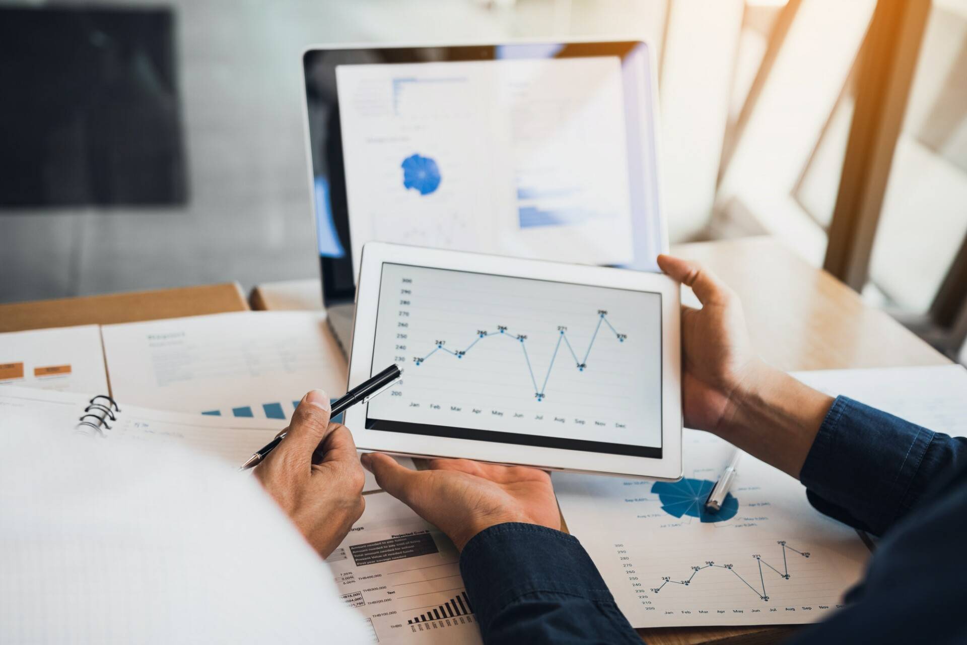 Business partnership coworkers using a tablet to chart company financial statements report.