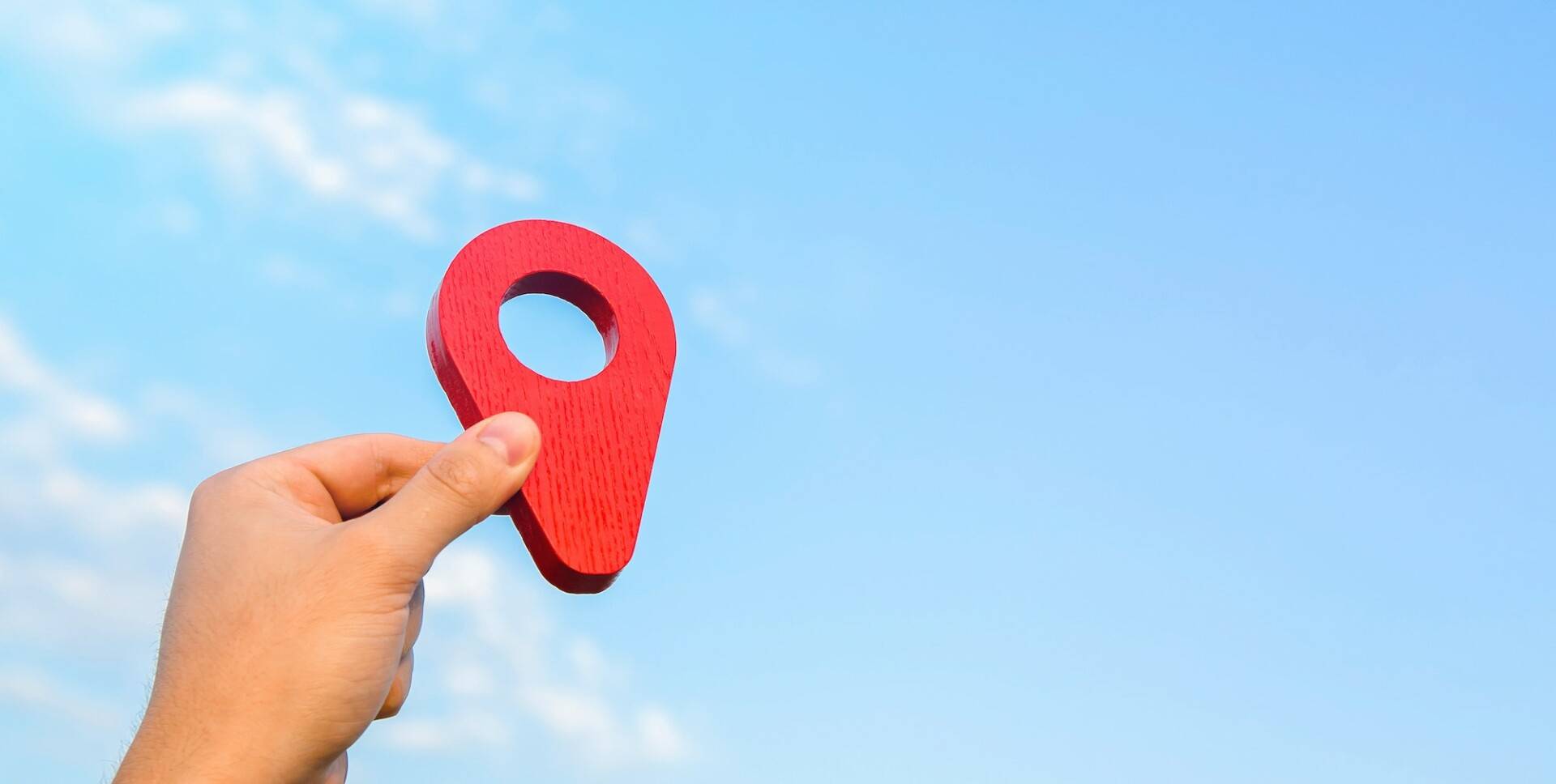 Holding a red location pin pointer in the sky.